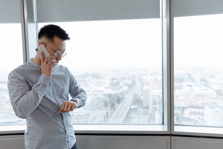 A Man Having A Phone Call While Looking At His Watch