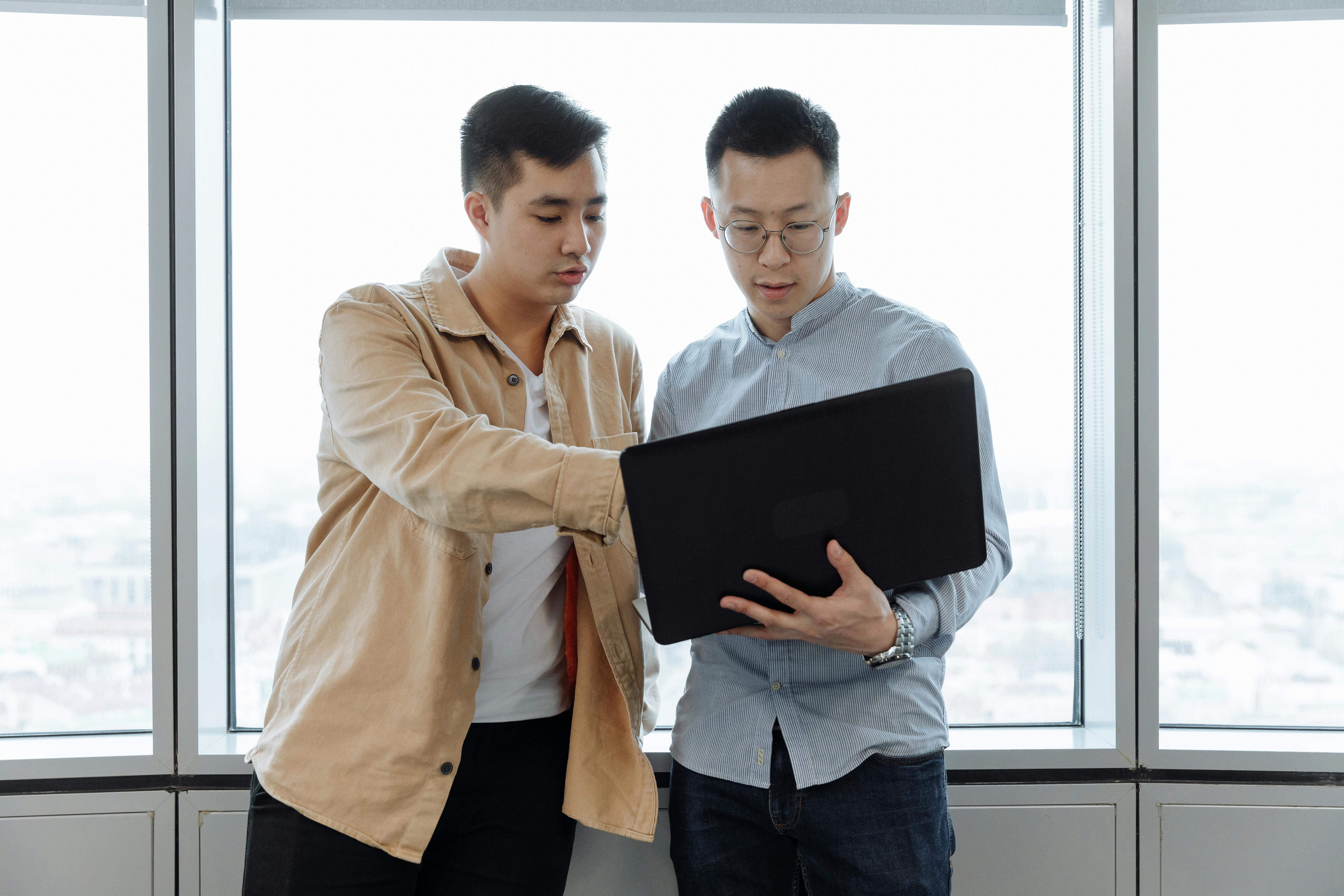 man in brown dress shirt holding black tablet computer