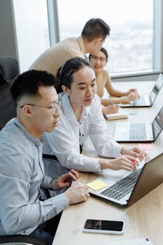 Young professionals collaborating on laptops in a modern office setting.