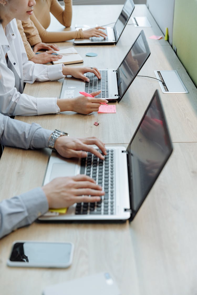 Close-up Shot Of People Busy Typing On Their Laptops