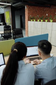 Two colleagues collaborating on a laptop in a modern, open-plan office space.