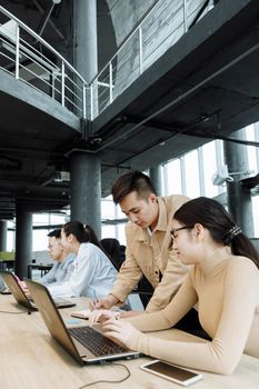 Colleagues working together on laptops in a contemporary office environment.