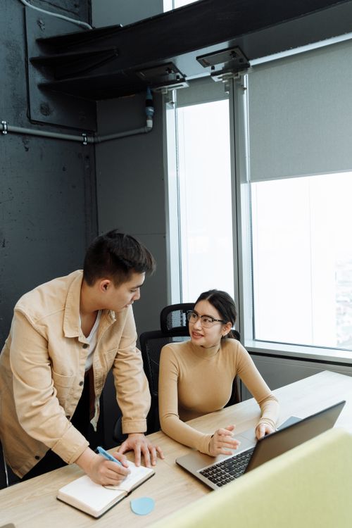 Free Two young adults discussing a project in a bright, modern office setting. Stock Photo