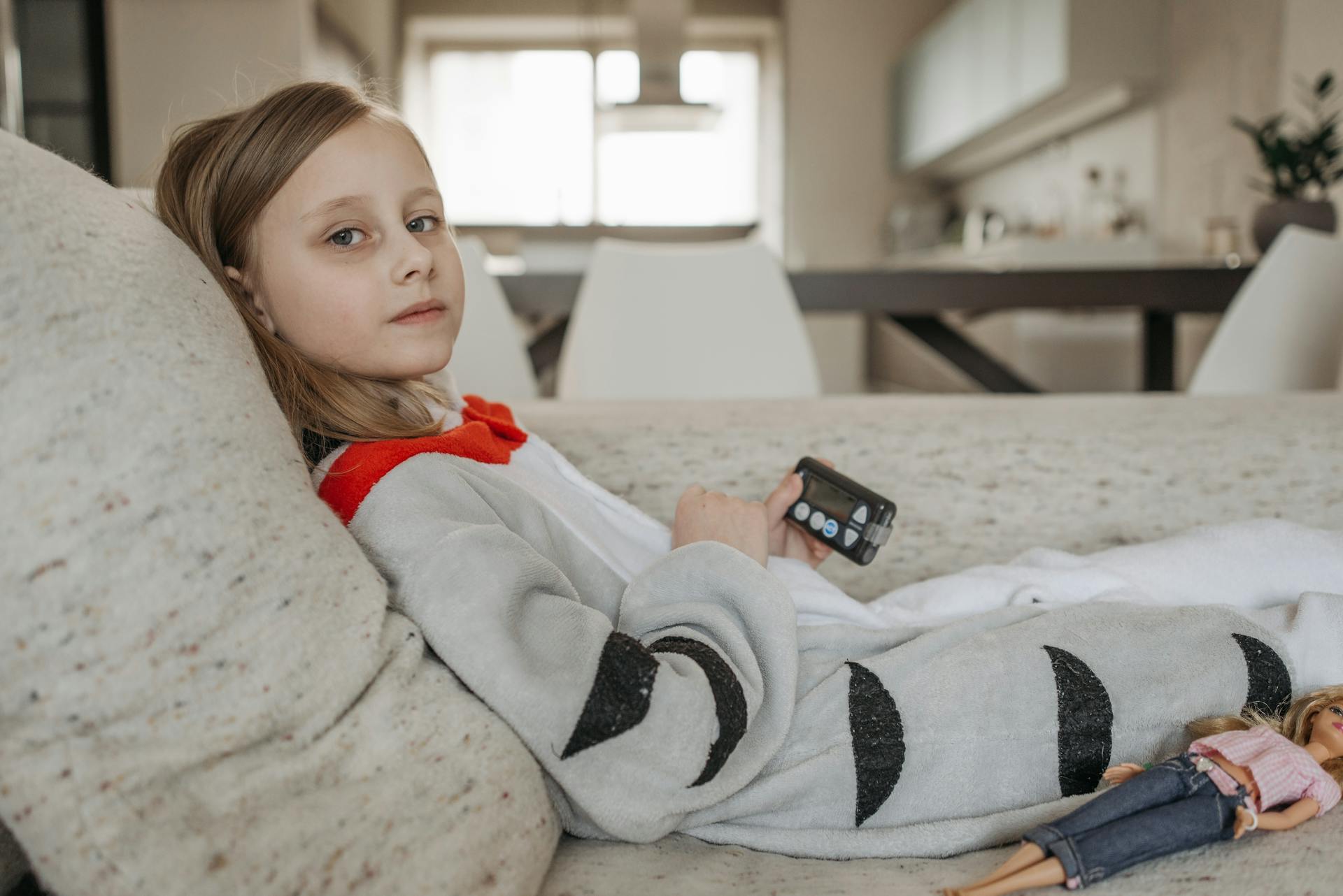 A Girl Holding an Insulin Pump while Sitting on a Sofa