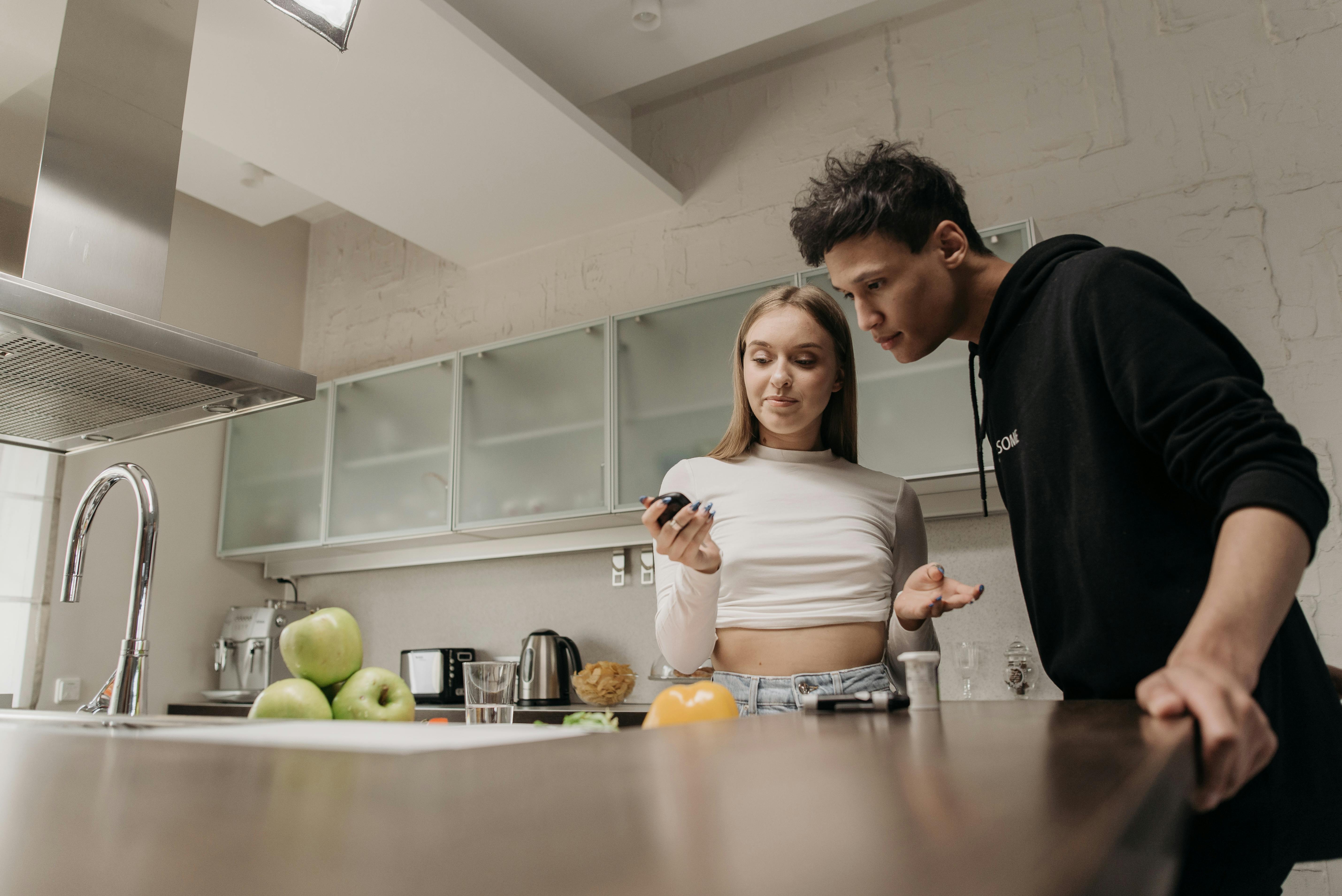 A couple discusses diabetes management while using a glucometer in a modern kitchen setting.