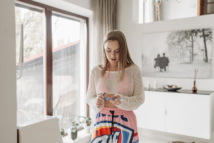 A Young Woman Holding An Insulin Pen Indoors