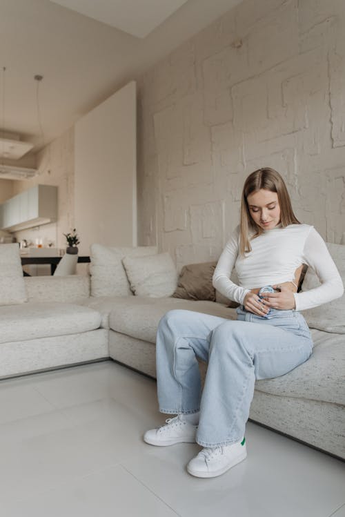 Free A Woman Putting Insulin Pump while Sitting on a Couch Stock Photo