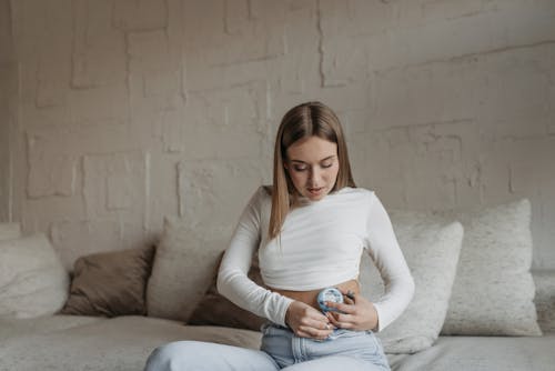 A Woman Wearing Crop Top while Busy Installing Insulin Pump on Her Abdomen