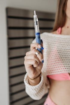 Close-up of a woman holding an insulin pen, emphasizing diabetes care.