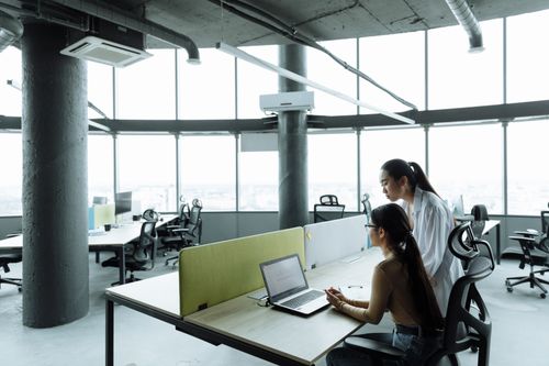 Free Two Asian women collaborating in a modern office environment focused on teamwork and innovation. Stock Photo