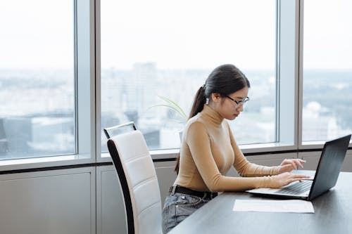 Woman in Brown Long Sleeve Shirt Using Laptop