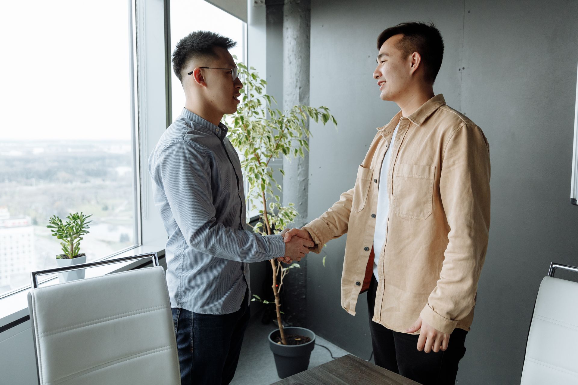 Two businessmen shaking hands in a modern office setting, symbolizing a successful business partnership.