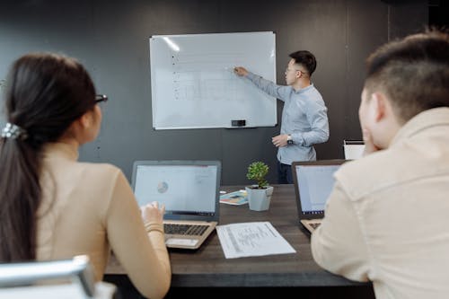 Man in Blue Long Sleeve Shirt Presenting in a Meeting