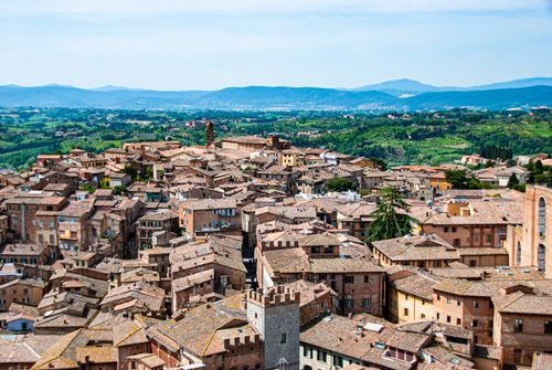 Free Discover the charming rooftops of Siena, Tuscany, captured from above with lush green hills in the backdrop. Stock Photo