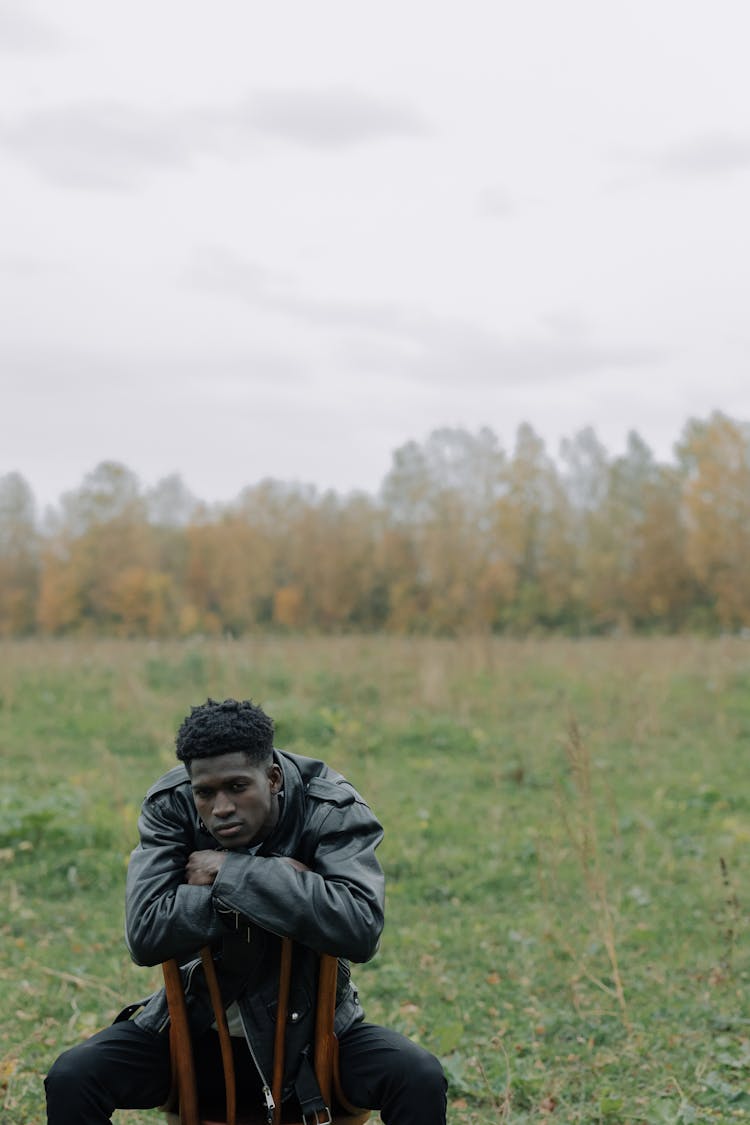 Man Wearing Leather Jacket Sitting On A Chair