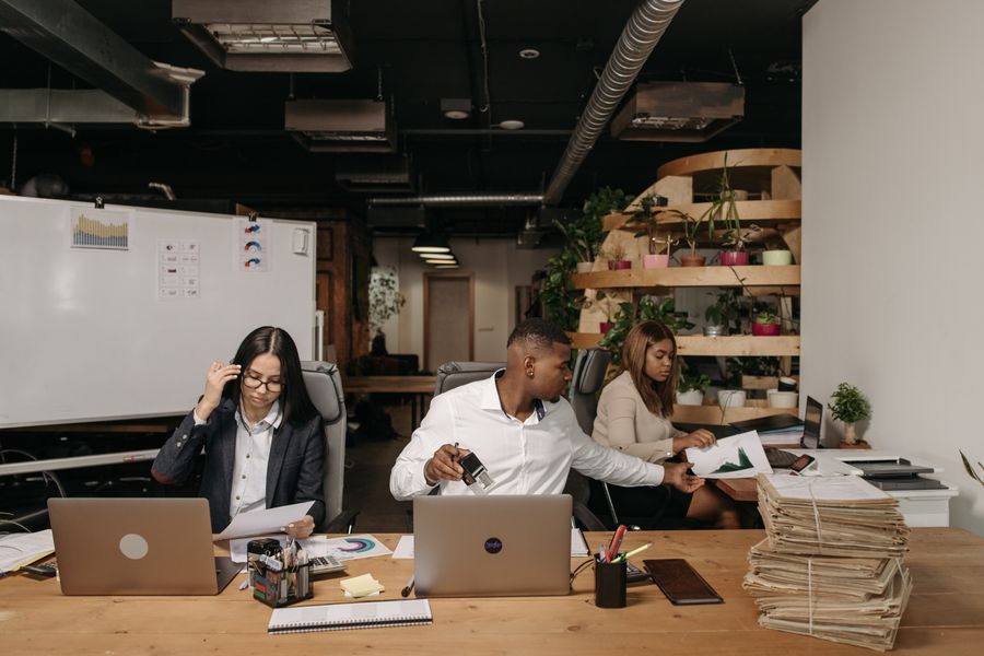Diverse team collaborating in a modern office setting with laptops and documents.
