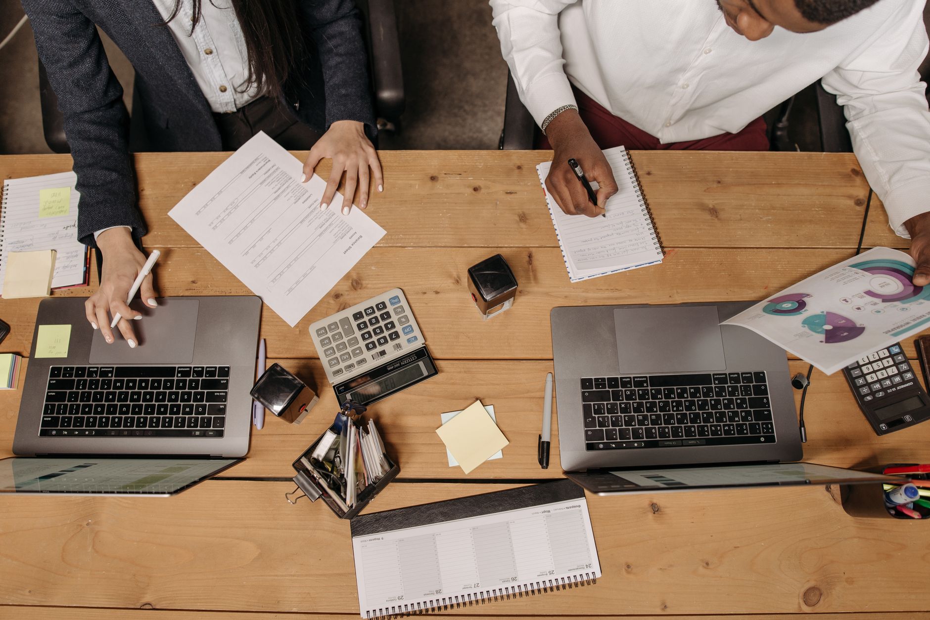 High-angle view of professionals working collaboratively with laptops and documents in an office.