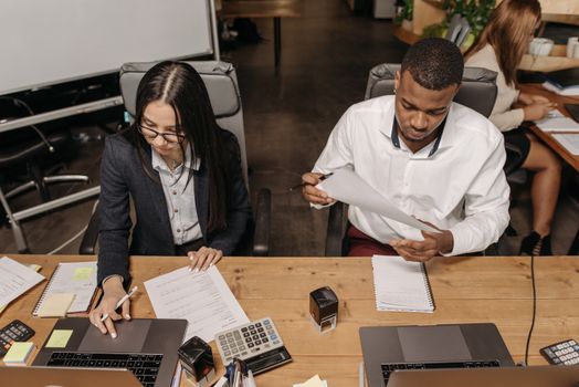 Multiracial office team working on financial documents, highlighting teamwork and productivity.