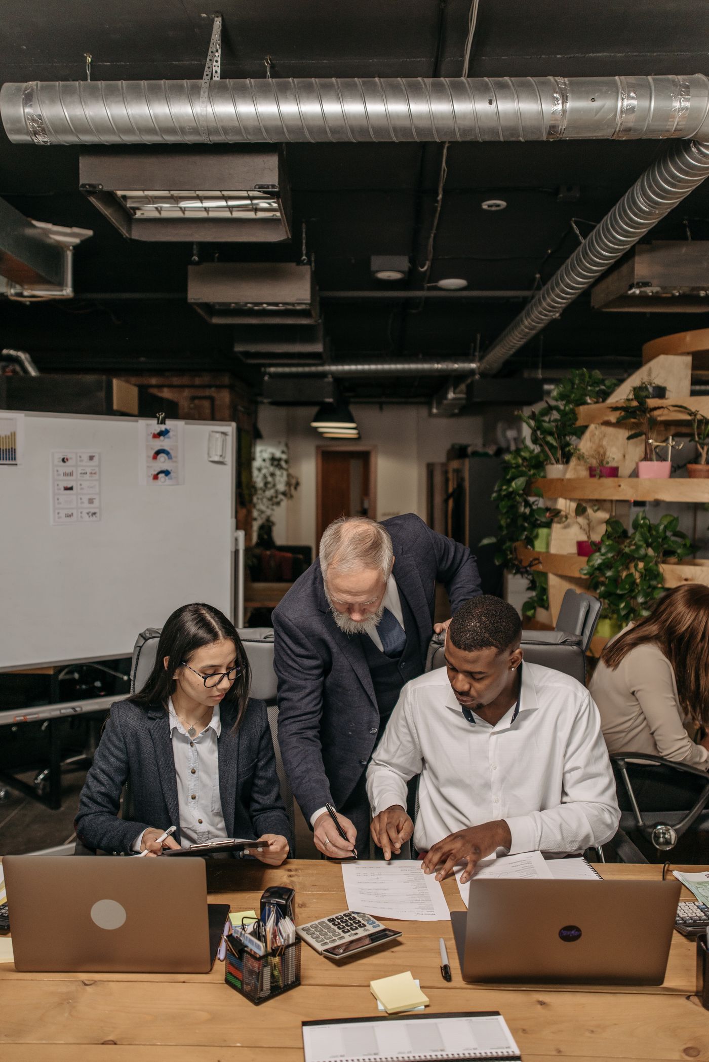 A diverse team collaborating around a table with laptops in a modern office