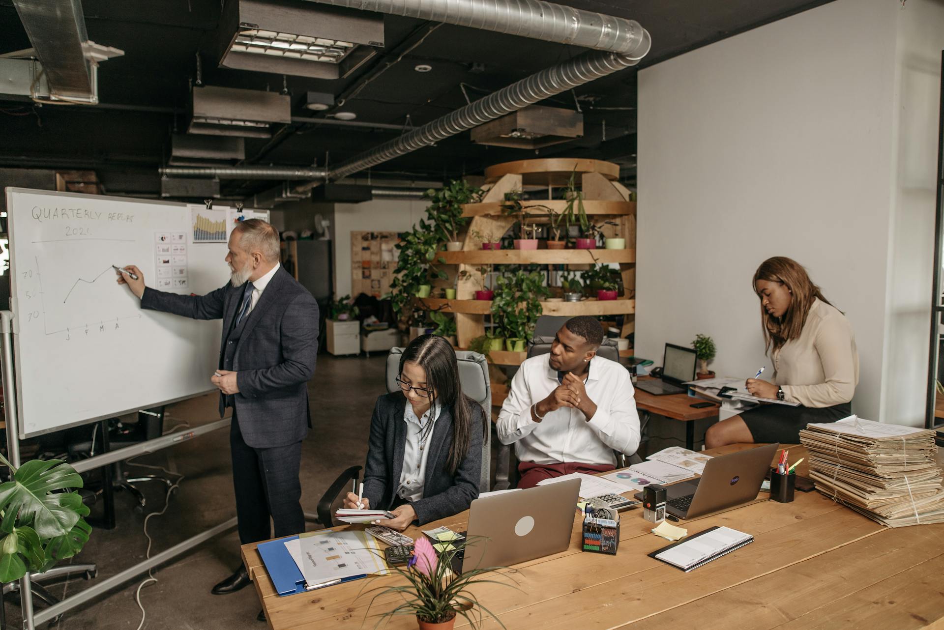 A diverse team collaborating around a whiteboard in a contemporary office setting, discussing quarterly data.