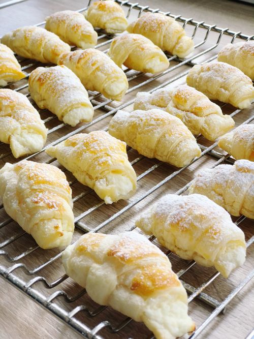 Free Delicious freshly baked puff pastries dusted with powdered sugar on a cooling rack. Stock Photo