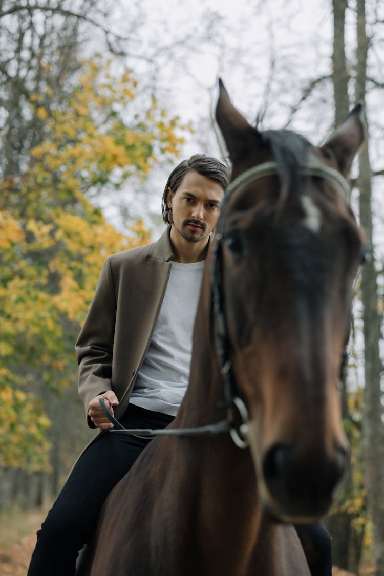 A Man Wearing Jacket Riding A Horse