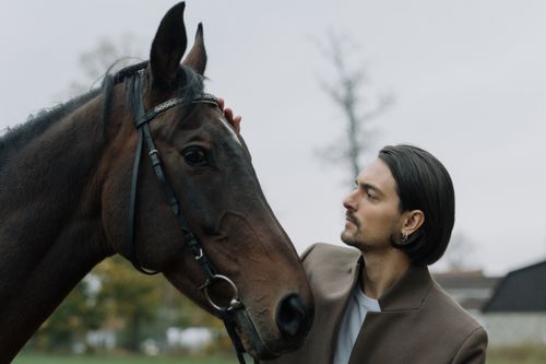 Free A man gently pats a horse in a serene outdoor setting, showcasing a bond between human and animal. Stock Photo