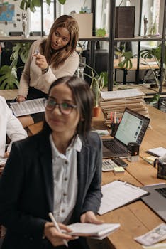 Asian and Black women collaborating in a vibrant office space, promoting teamwork.