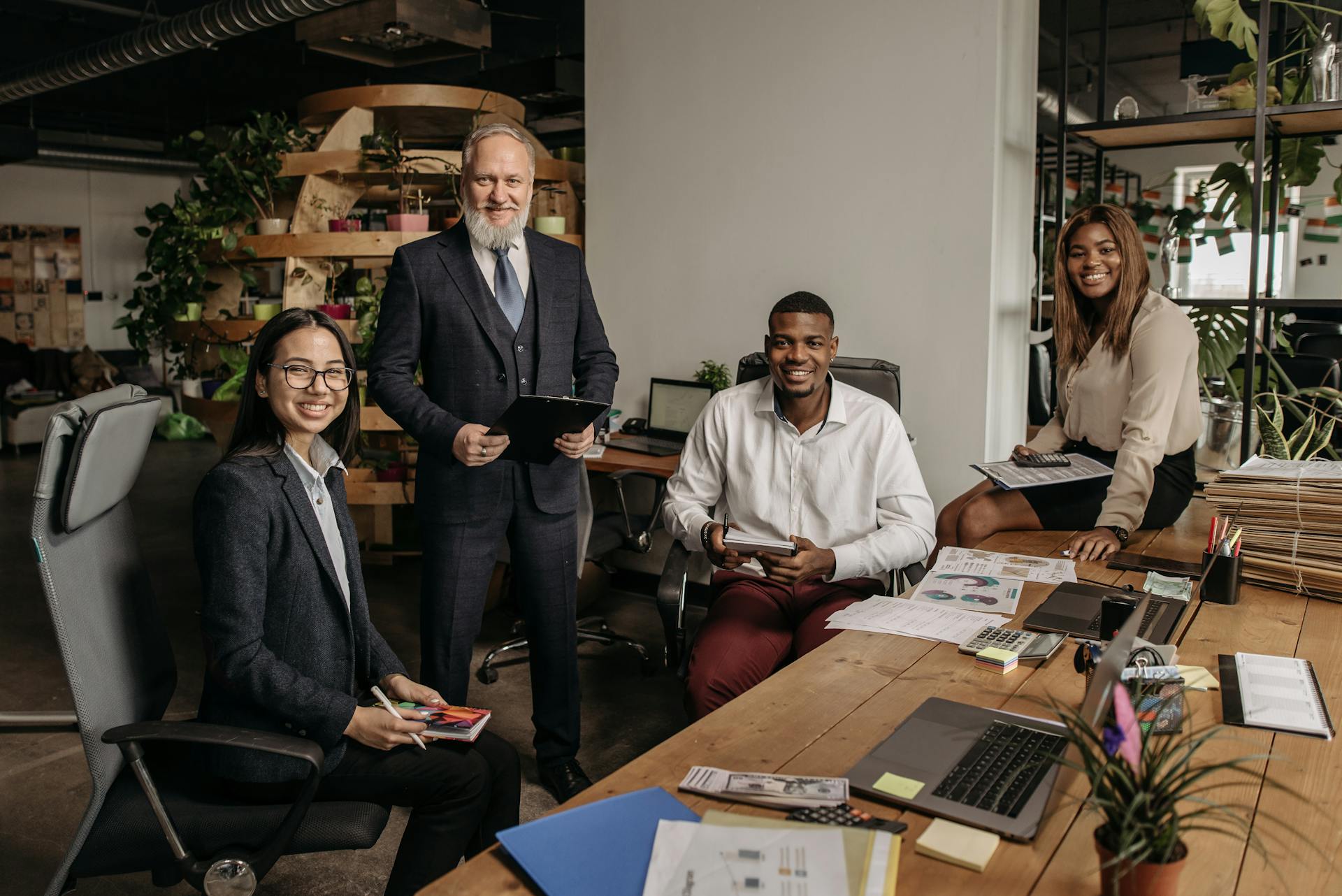 Office Workers Sitting at the Desk and a Boss Standing near Them and Smiling