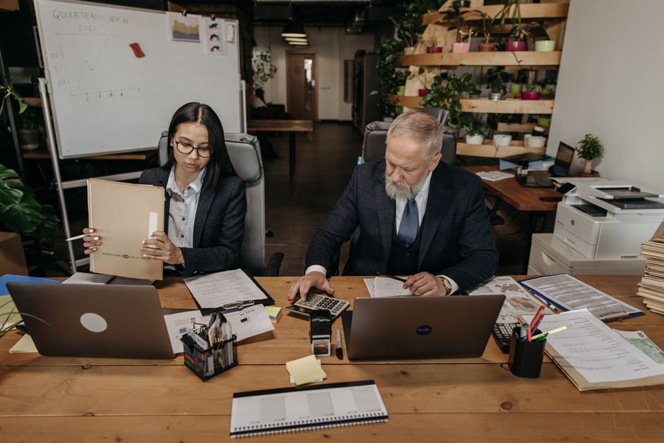 Profesionales de negocios en una oficina moderna trabajando de manera colaborativa en escritorios con laptops.