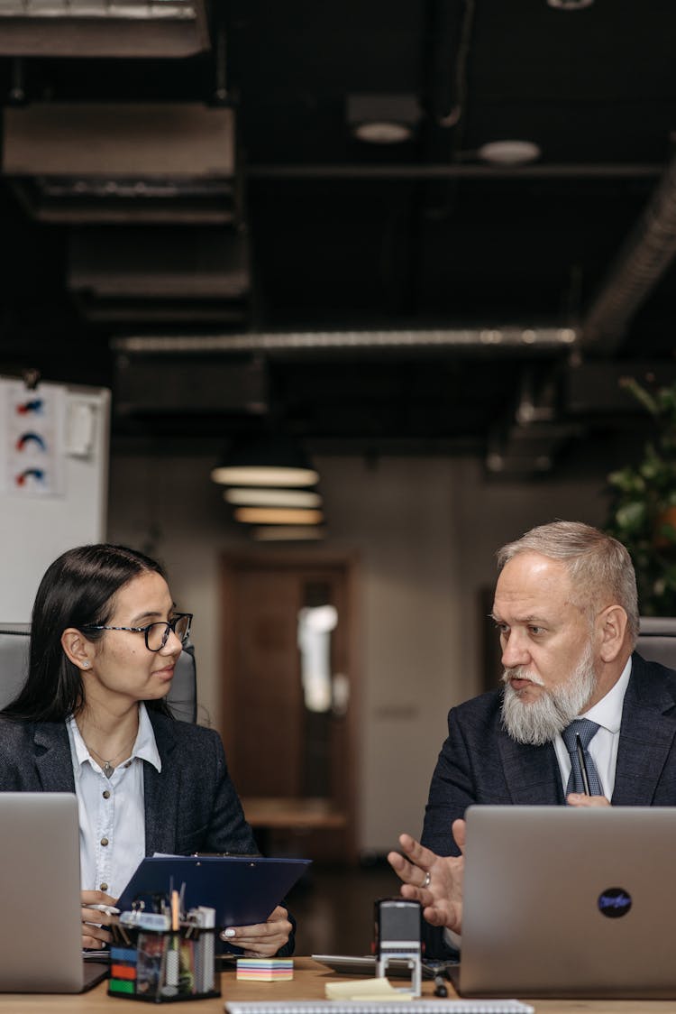 Bearded Man And Woman In Black Blazers With Laptops