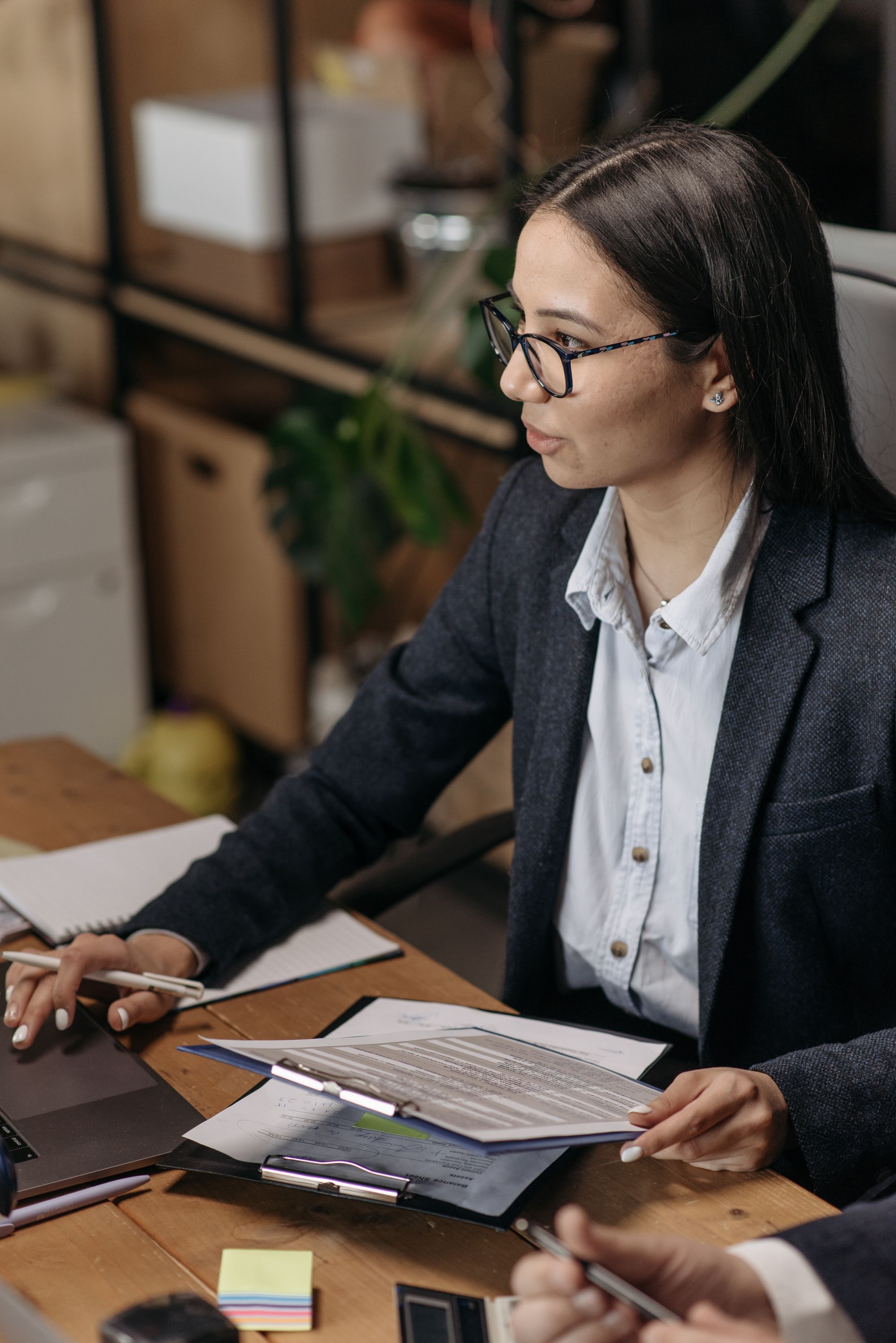 An account executive in a blazer working through deal documents at her desk