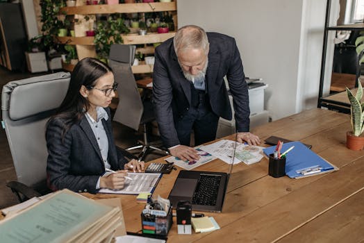 Business professionals having a discussion at office desk, reviewing documents and strategies.