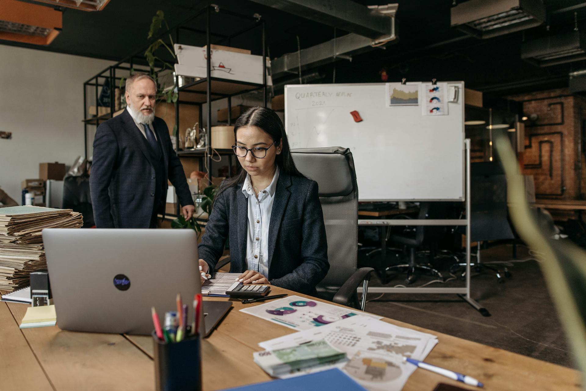 Business professionals collaborating in a modern office setting with laptop and documents.