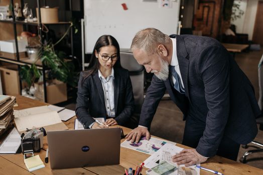 Business meeting with two professionals discussing charts and data at a desk.