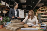 Woman in White Long Sleeve Shirt Standing Beside Woman in Black Blazer