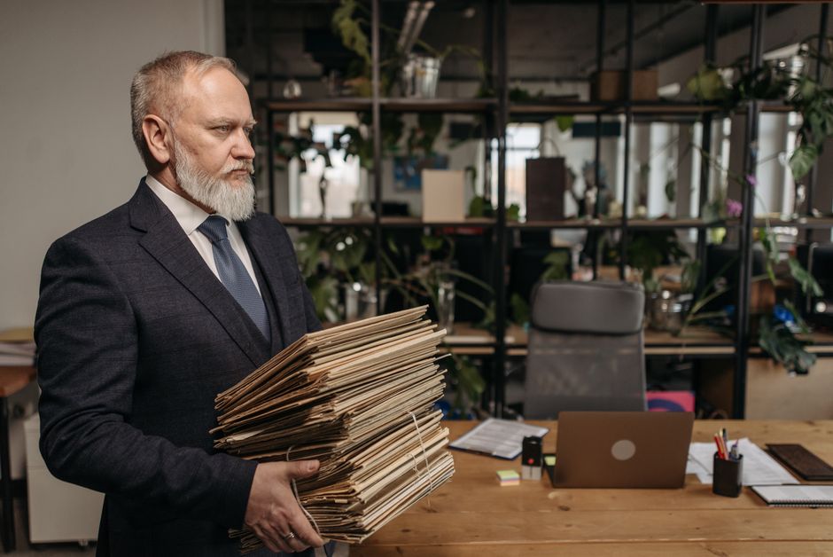 Empresario senior sosteniendo archivos en un entorno de oficina moderna, encarnando dedicación y profesionalismo.