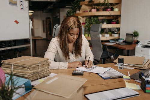 Free Businesswoman focused on paperwork in an organized office setting. Stock Photo