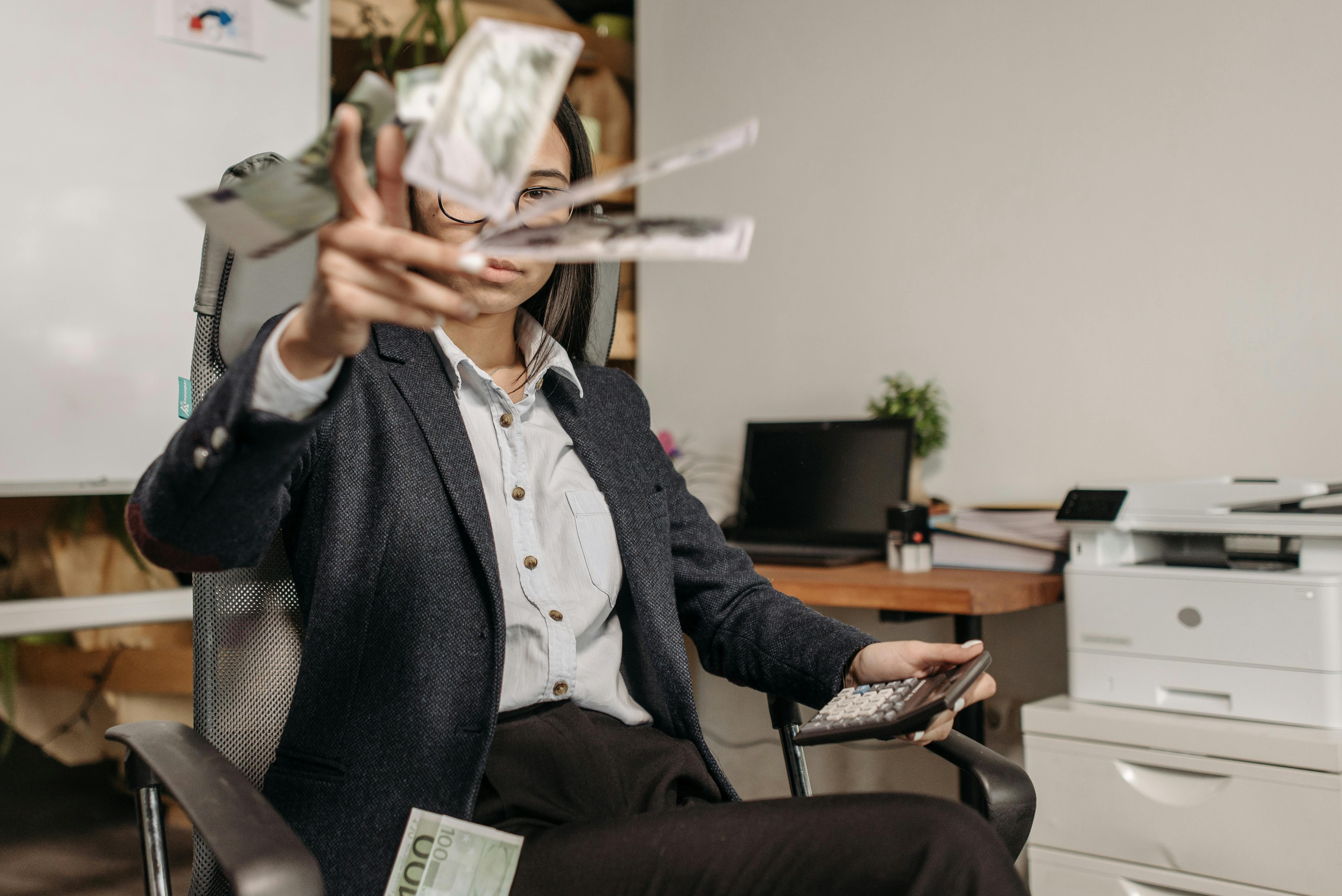 woman in suit sitting at office and throwing money