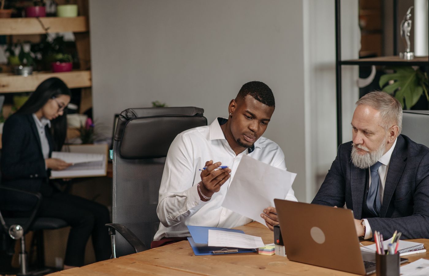 Business professionals discussing documents in a modern office environment with focus on teamwork and collaboration.