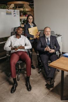Three professionals in a contemporary office setting, engaged with documents.