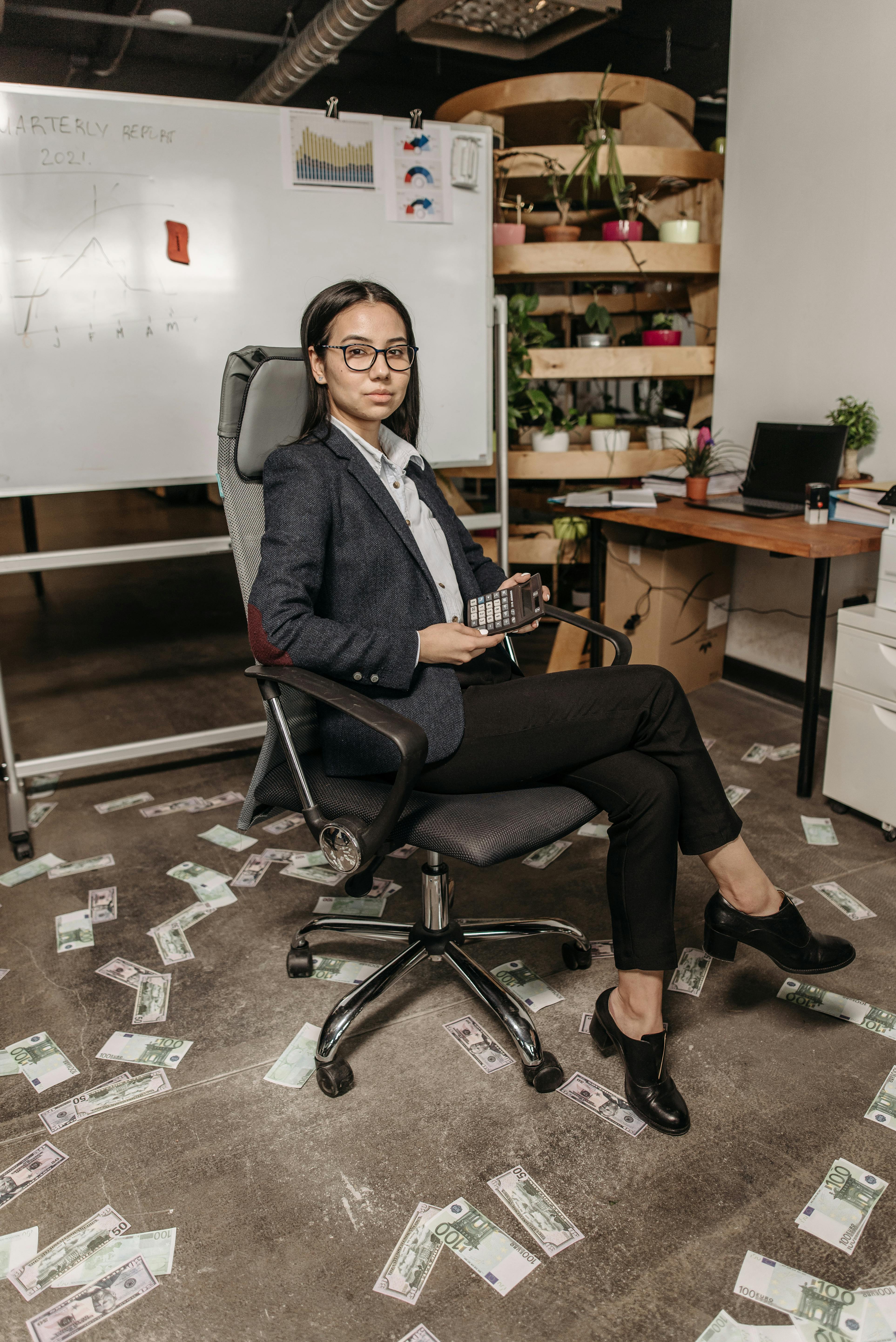 woman sitting on a gray swivel chair holding a calculator