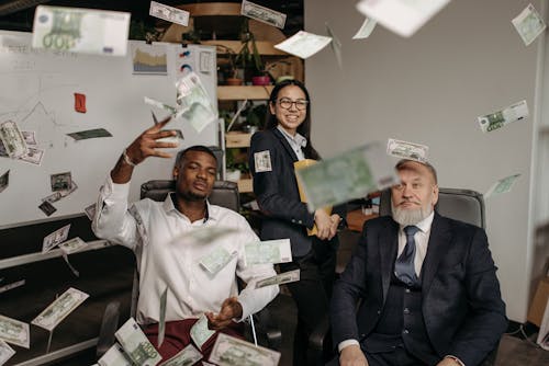Paper Money Falling Around the People in Business Attire in the Office