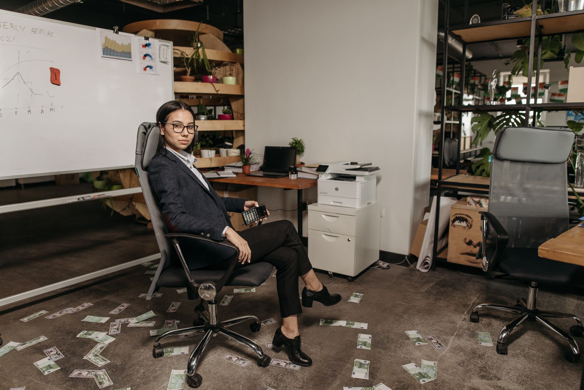 Confident woman in office chair surrounded by banknotes with a calculator.
