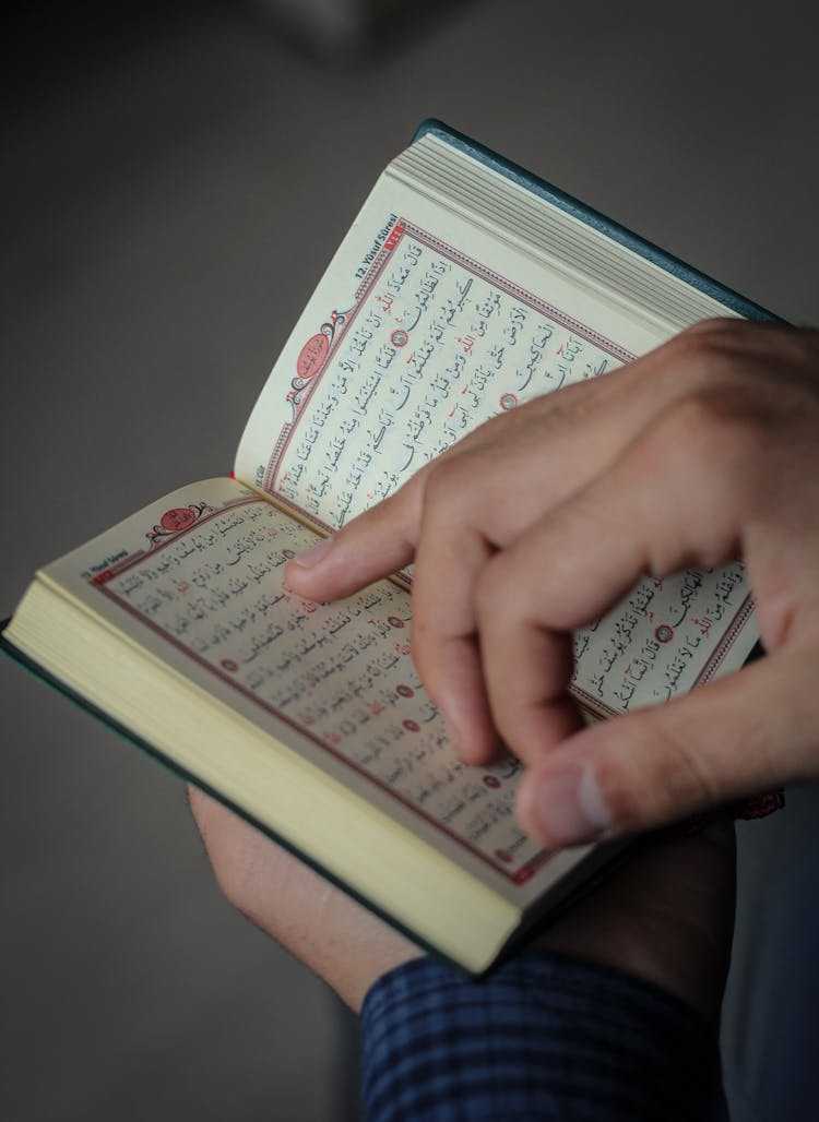 Crop Person Turning Page Of Koran