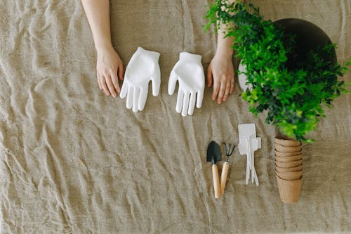 A Person Hand on Brown Textile Beside White Gloves