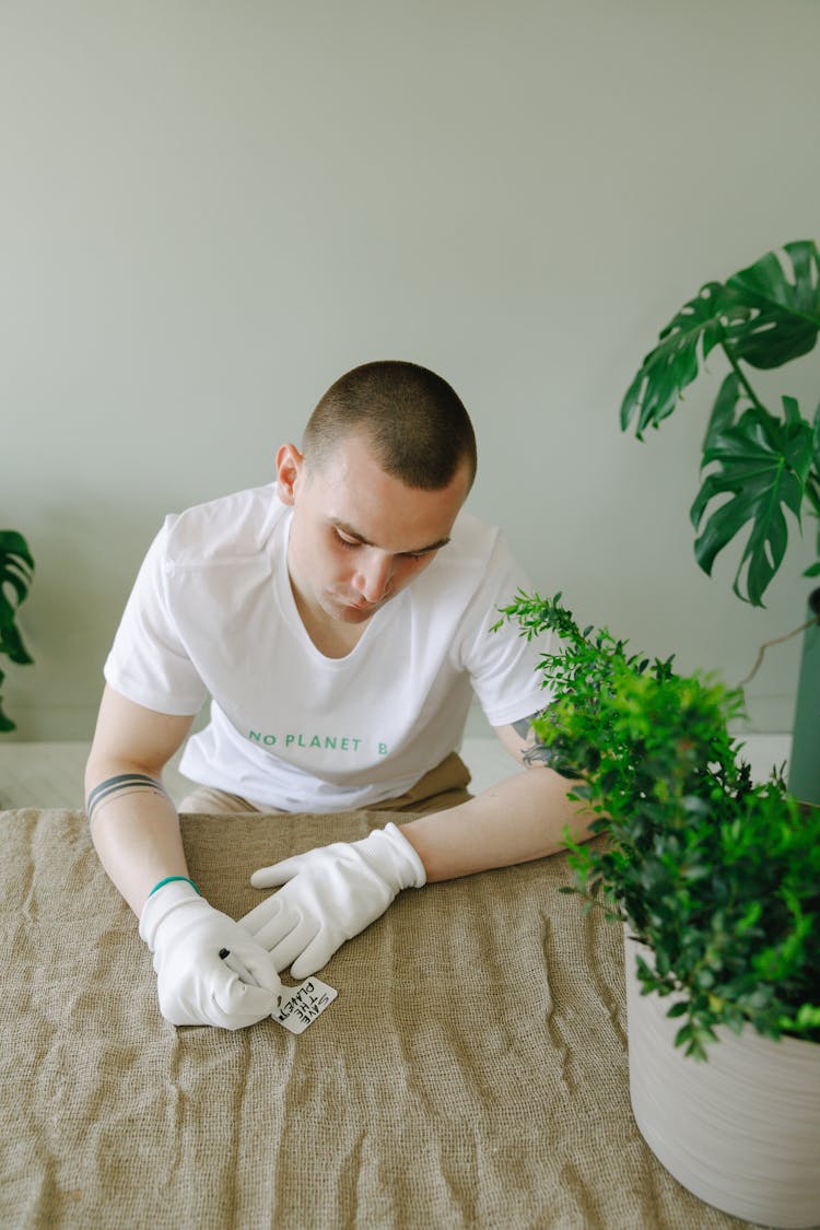 A Man Writing On A Plant Label