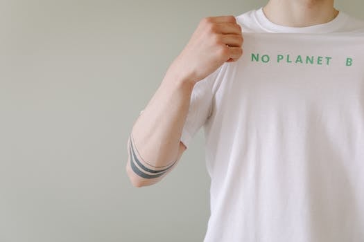 Close-up of a person showcasing a T-shirt with a 'No Planet B' environmental message.