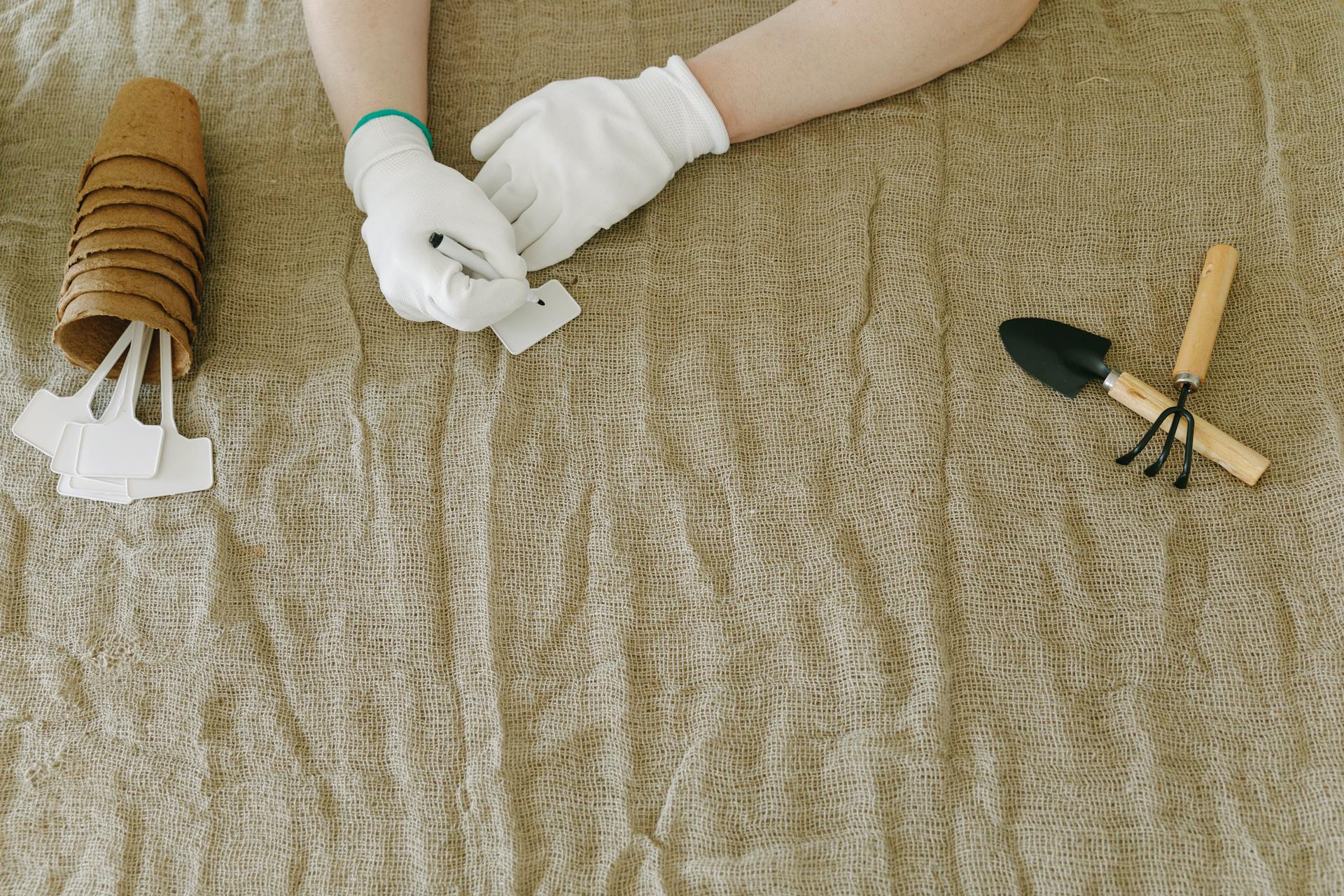 Person in White Gloves Writing on Plant Tags