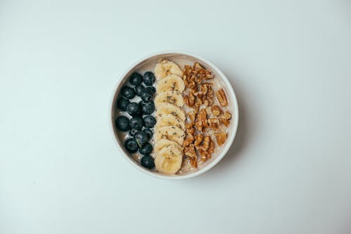 An Oatmeal with Fresh Fruits Topping on a White Surface